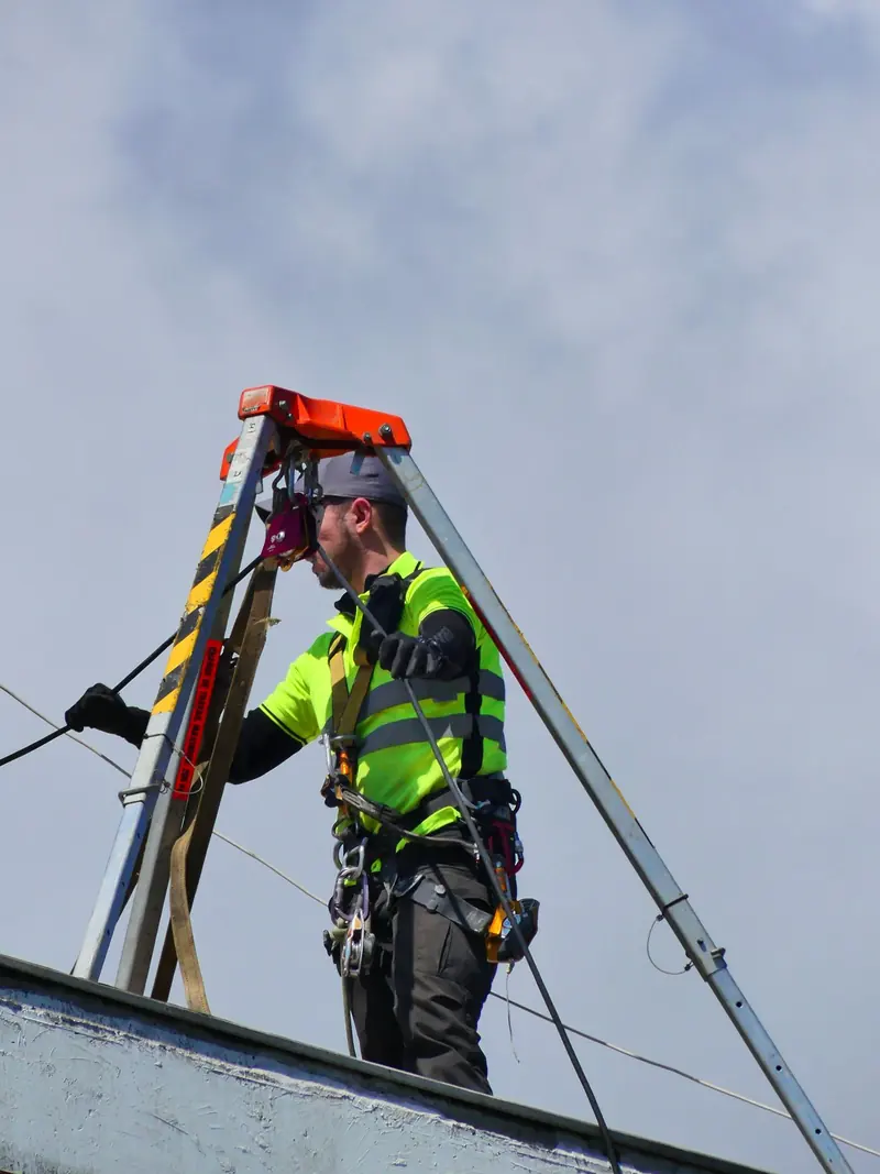Industrijski alpinista postavlja sidrište na krovu zgrade