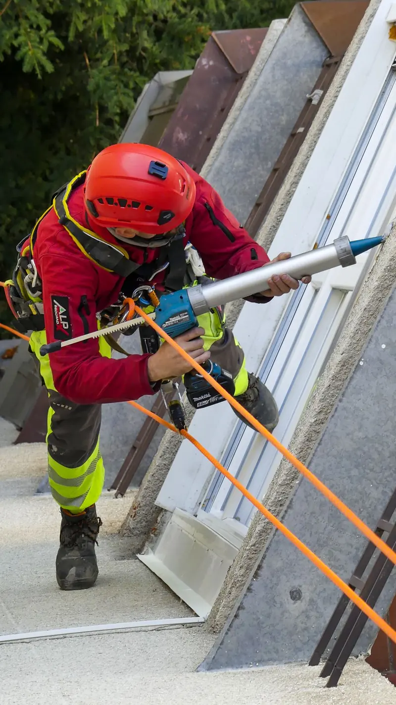 Industrijski alpinista na krovu, sidrenje užeta na tronošcu